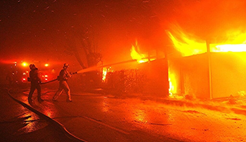 2 firefighters putting out a house fire during the Getty Fire.