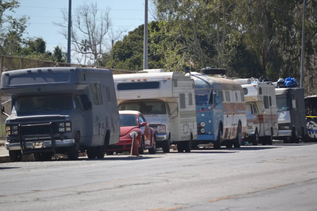 A line of motor homes and camper trailers parked along a street.