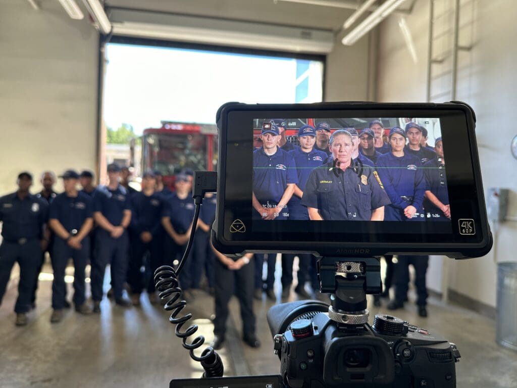 A screen displaying a fire department team as they are being recorded, with the subjects out of focus in the background.