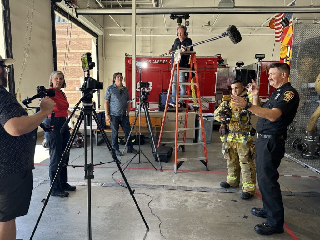 A firefighter and public safety officer being filmed by an AV team in their station.