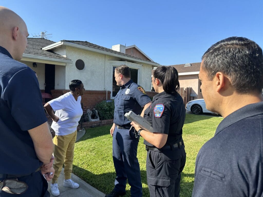 Four public safety members from MySafe:LA speaking to a homeowner outside their home on a sunny day.