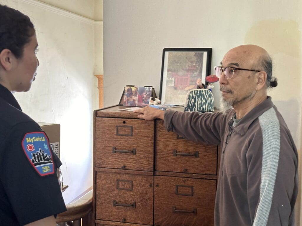 A female MySafe:LA representative speaking to an older man inside his home.