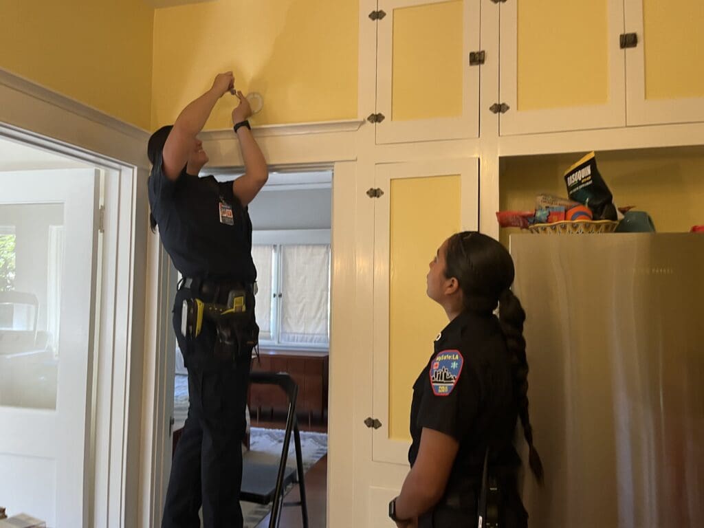 Two female members of MySafe:LA installing a smoke alarm in a home.
