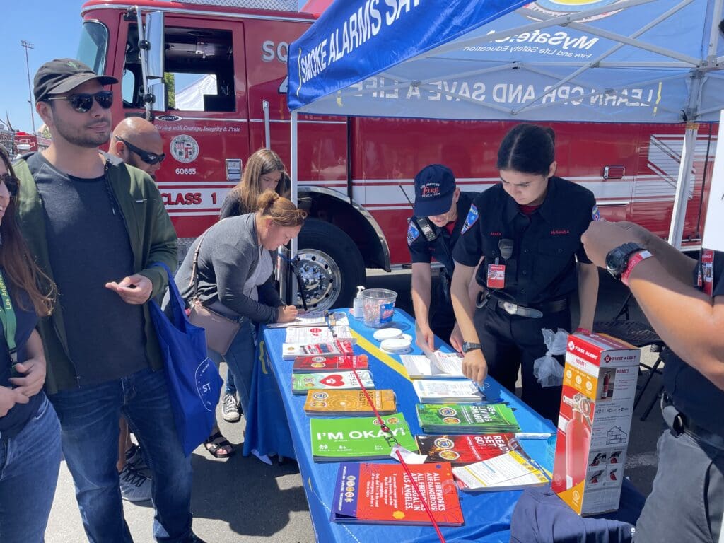 Men and women attending San Pedro Fleet Week looking at printed informational resources at a table hosted by MySafe:LA