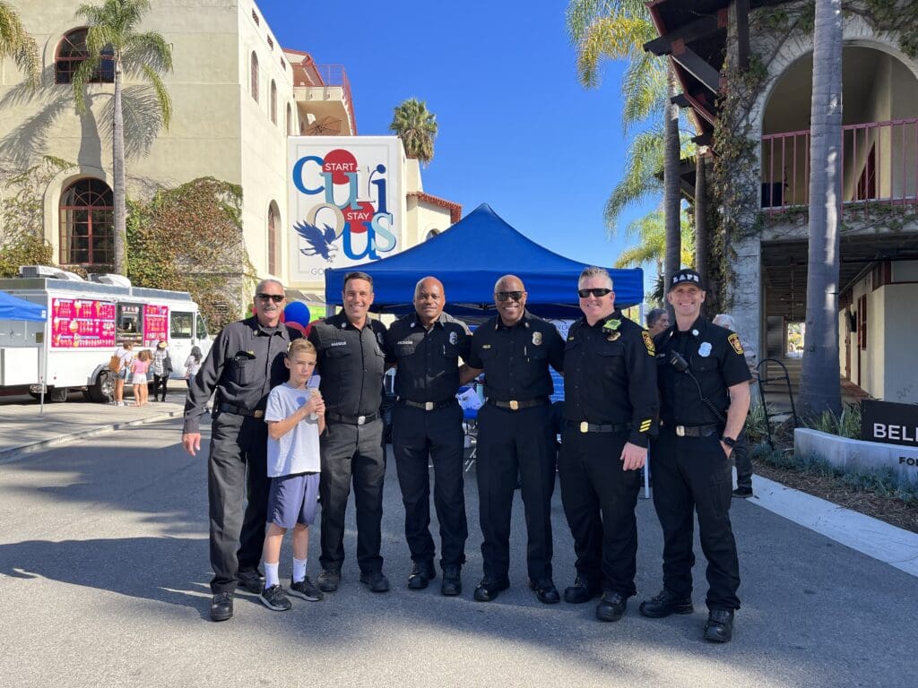 Team members from MySafe:LA standing in front of a fair with a little boy who is eating ice cream.